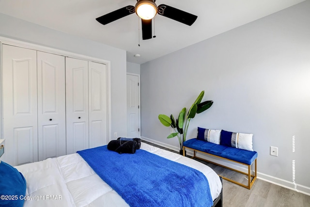 bedroom featuring a ceiling fan, a closet, baseboards, and wood finished floors
