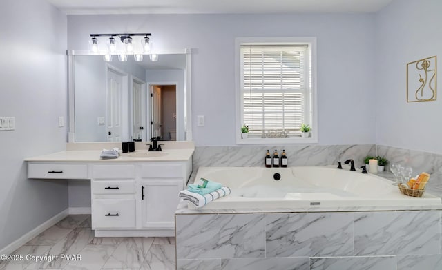 full bath with a garden tub, baseboards, marble finish floor, and vanity