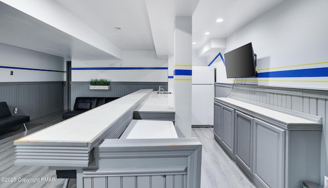 interior space with light wood finished floors, wainscoting, a sink, and recessed lighting