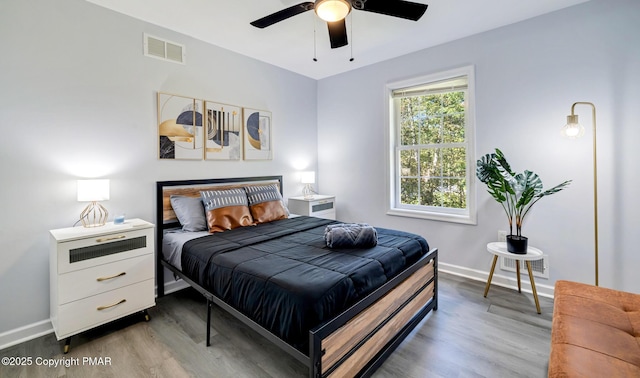 bedroom with ceiling fan, wood finished floors, visible vents, and baseboards