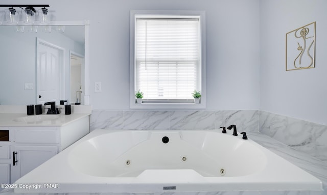 bathroom with a tub with jets and vanity