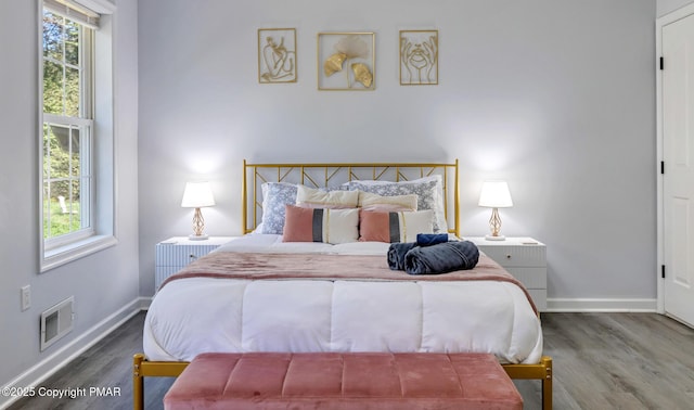 bedroom featuring visible vents, baseboards, and wood finished floors