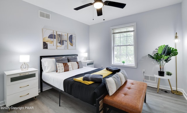 bedroom with wood finished floors, visible vents, and baseboards