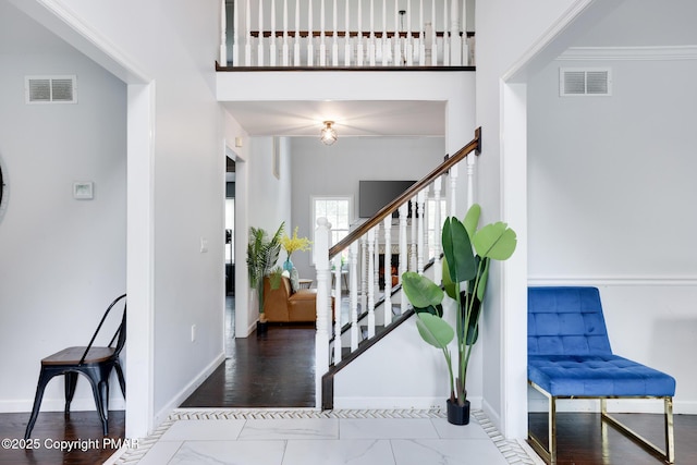 entryway with baseboards, a high ceiling, and visible vents