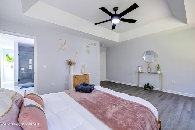 bedroom with ceiling fan, ensuite bathroom, and a raised ceiling