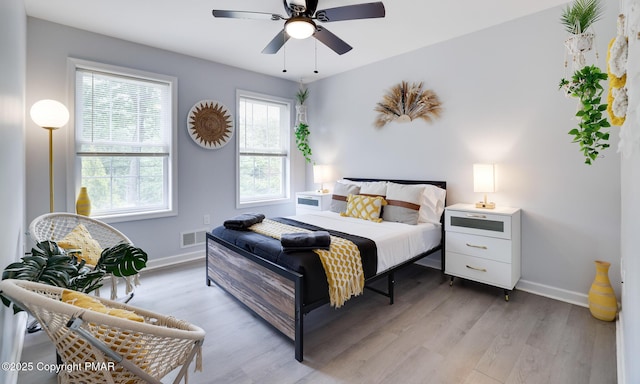 bedroom with light wood-style floors, baseboards, visible vents, and ceiling fan
