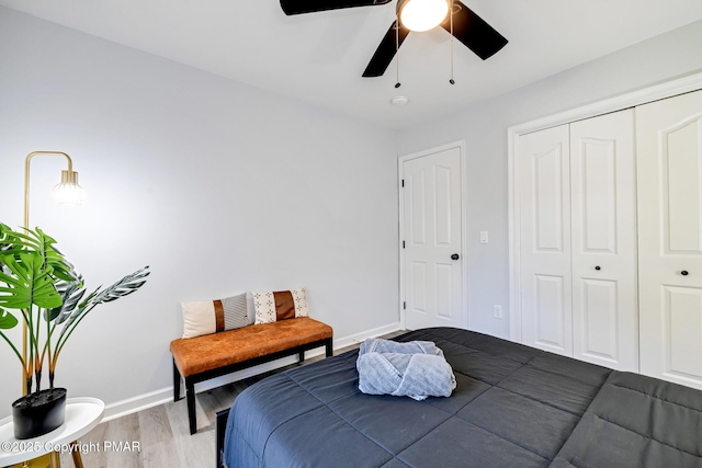 bedroom featuring ceiling fan, a closet, wood finished floors, and baseboards