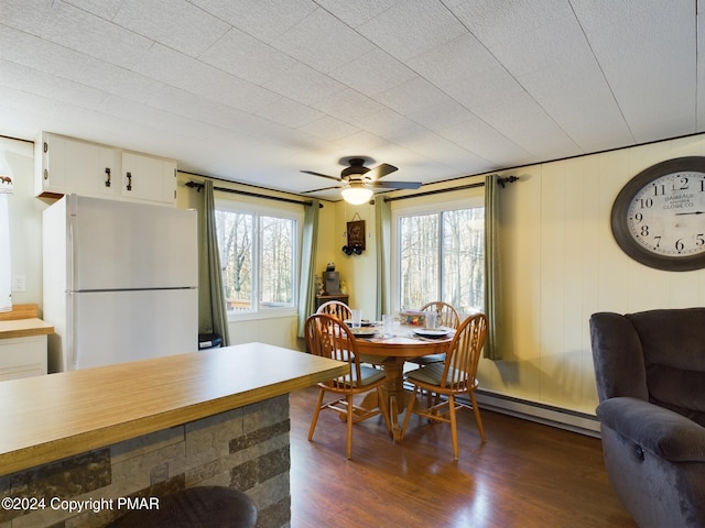 dining space featuring dark hardwood / wood-style flooring, ceiling fan, a healthy amount of sunlight, and baseboard heating