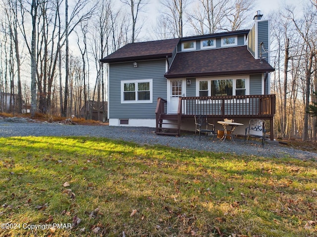 rear view of property featuring a deck and a lawn