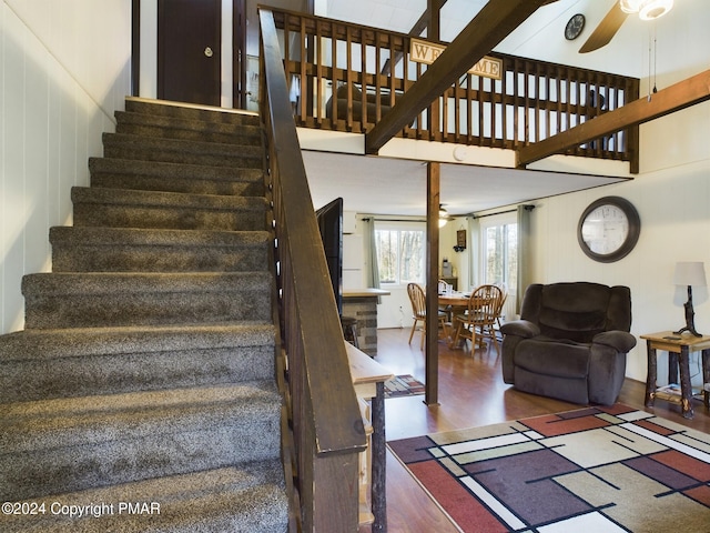 staircase featuring ceiling fan, wood-type flooring, and a high ceiling