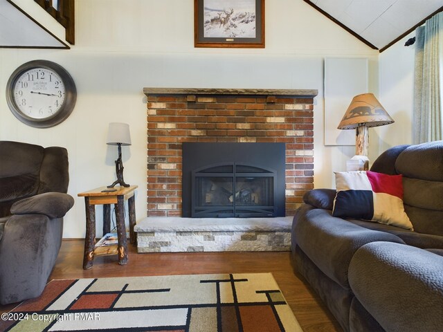 living room featuring lofted ceiling, dark wood-type flooring, and a brick fireplace