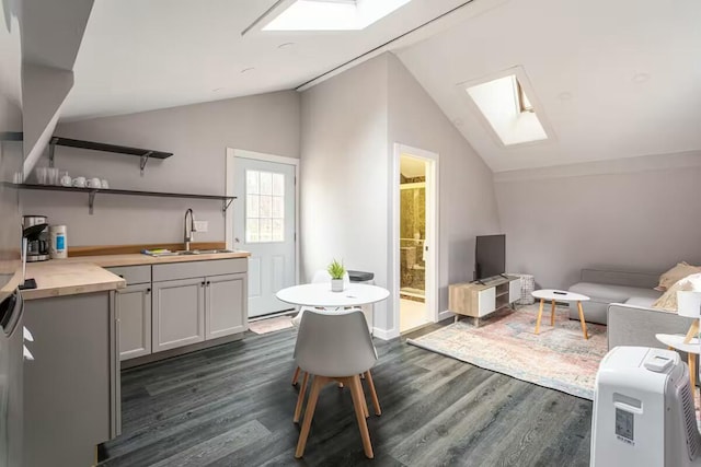 kitchen featuring dark wood finished floors, vaulted ceiling with skylight, and a sink