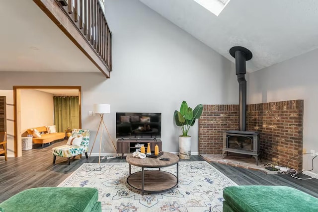 living area featuring high vaulted ceiling, a wood stove, baseboards, and wood finished floors