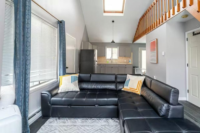 living area with vaulted ceiling with skylight, baseboards, and a baseboard radiator