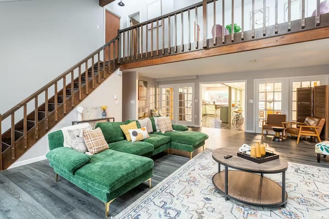 living room featuring baseboards, stairway, french doors, a high ceiling, and wood finished floors