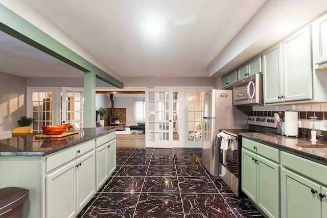 kitchen featuring marble finish floor, tasteful backsplash, stainless steel appliances, french doors, and green cabinetry