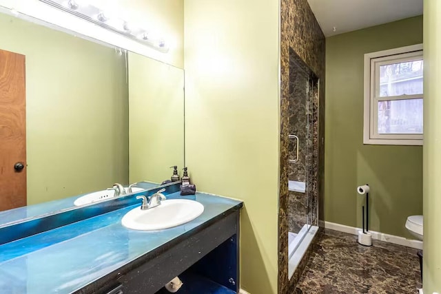 bathroom featuring a stall shower, toilet, vanity, and baseboards