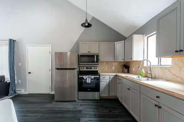 kitchen featuring a sink, appliances with stainless steel finishes, light countertops, dark wood-style flooring, and vaulted ceiling