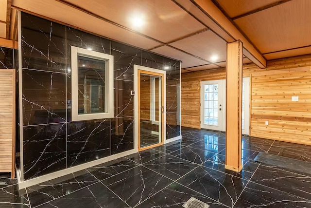 unfurnished room featuring marble finish floor and wood walls