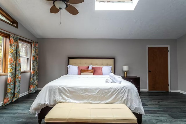 bedroom with lofted ceiling with skylight, a ceiling fan, baseboards, and wood finished floors