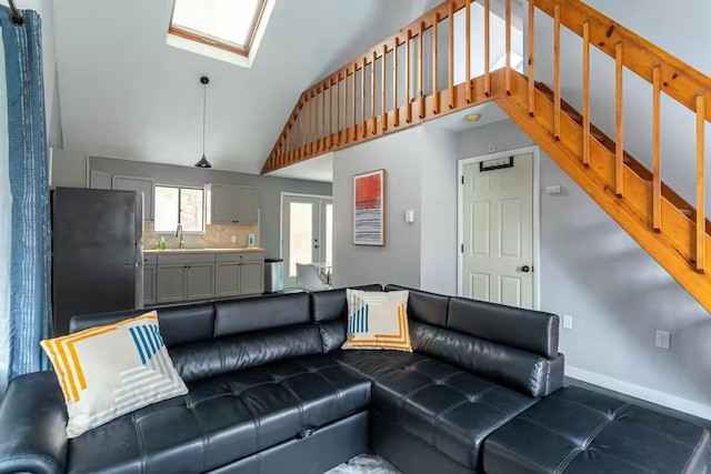 living room with a skylight, french doors, baseboards, and high vaulted ceiling