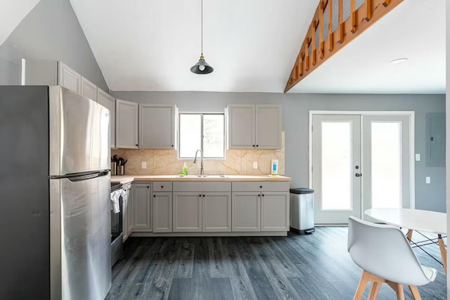 kitchen with light countertops, lofted ceiling, decorative backsplash, freestanding refrigerator, and a sink