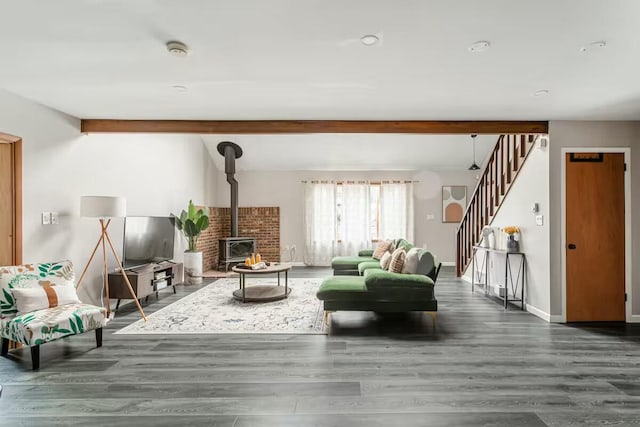 living area featuring stairway, a wood stove, baseboards, and wood finished floors