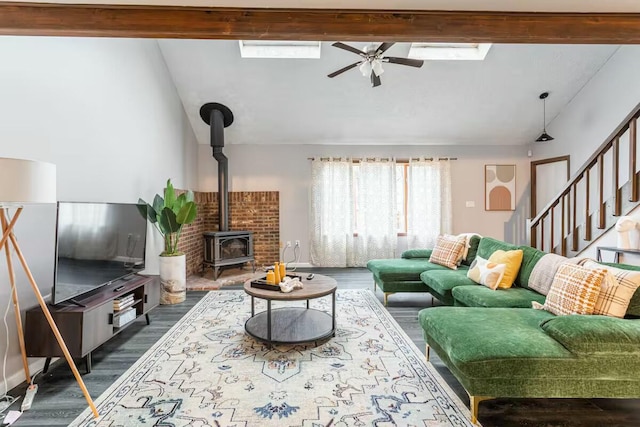 living room featuring stairs, vaulted ceiling with skylight, dark wood-style flooring, and a wood stove