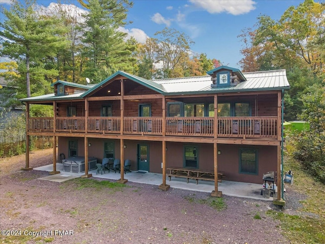 rear view of property with metal roof, a patio area, and a wooden deck