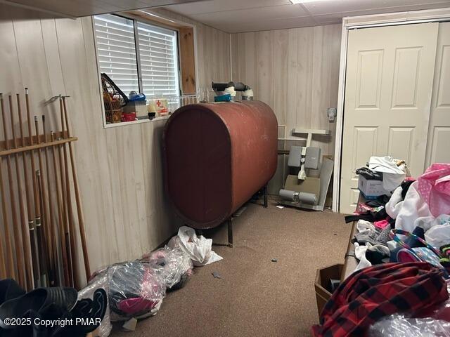 home office featuring carpet flooring, wooden walls, and heating fuel