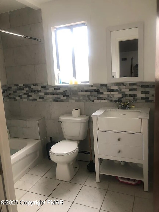 bathroom with tile walls, a bathtub, vanity, tile patterned floors, and toilet