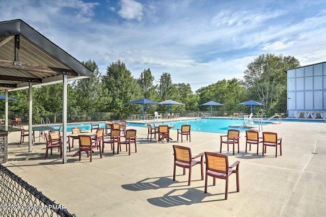 community pool with fence and view of wooded area