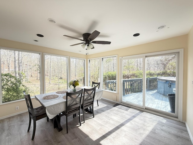 sunroom with a hot tub, a deck, baseboards, and wood finished floors