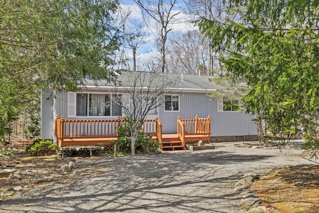 view of front of house featuring a wooden deck and roof with shingles