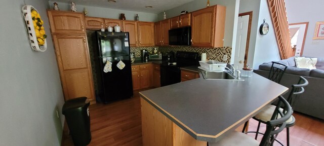 25 Byron Ln, Albrightsville, PA 18210 - kitchen featuring black appliances, a sink, wood finished floors, decorative backsplash, and a breakfast bar