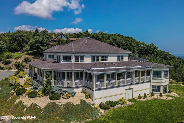 back of property with a yard, a sunroom, and stucco siding