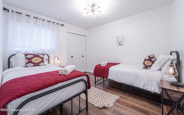 bedroom featuring a chandelier, a closet, baseboards, and wood finished floors