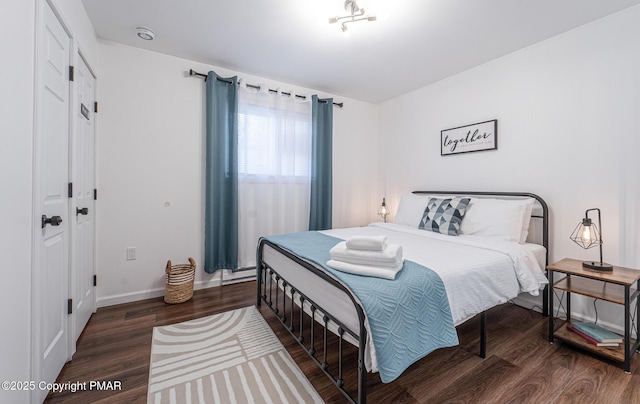 bedroom featuring baseboard heating, baseboards, and wood finished floors