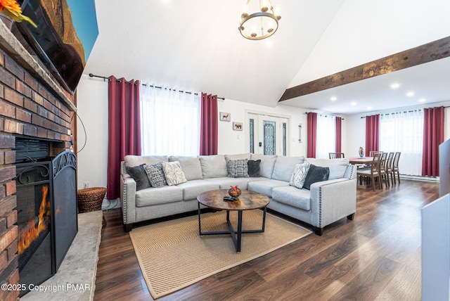 living area with a notable chandelier, a fireplace, high vaulted ceiling, and dark wood-type flooring