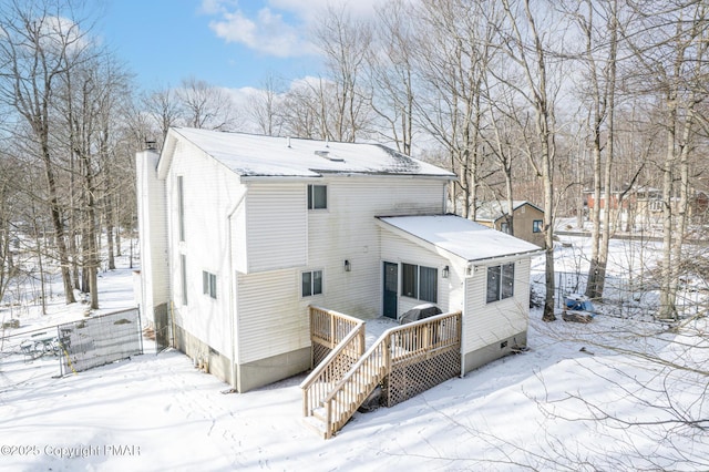 snow covered back of property featuring a chimney