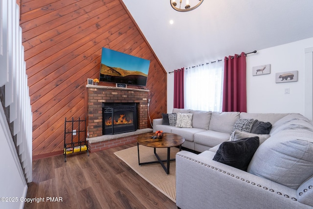 living area with lofted ceiling, wooden walls, a fireplace, and wood finished floors