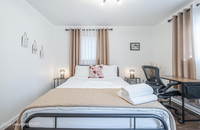 bedroom with baseboard heating and wood finished floors