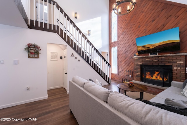 living area featuring stairs, a fireplace, wood finished floors, and a towering ceiling