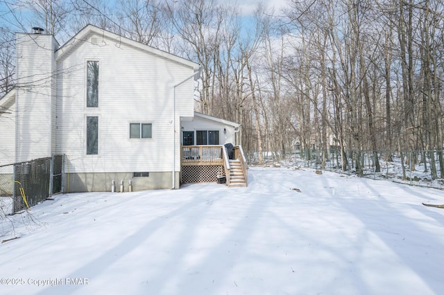 snow covered property with fence, a chimney, and a wooden deck