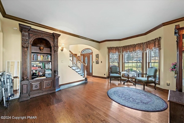 living area with arched walkways, crown molding, stairway, wood finished floors, and baseboards