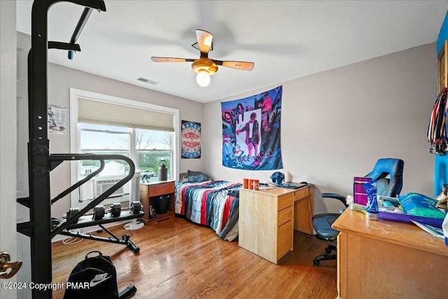 bedroom with a ceiling fan, visible vents, and wood finished floors