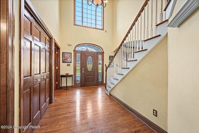 foyer entrance with an inviting chandelier, stairway, baseboards, and wood finished floors