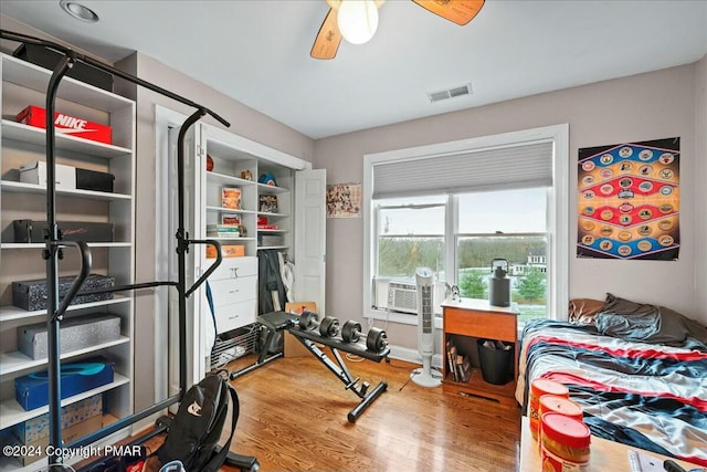 workout room featuring cooling unit, ceiling fan, visible vents, and wood finished floors