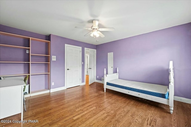 unfurnished bedroom with ceiling fan, wood finished floors, and baseboards