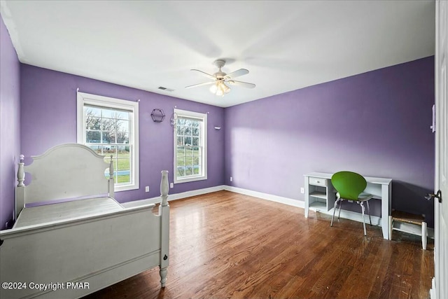 bedroom with ceiling fan, wood finished floors, visible vents, and baseboards